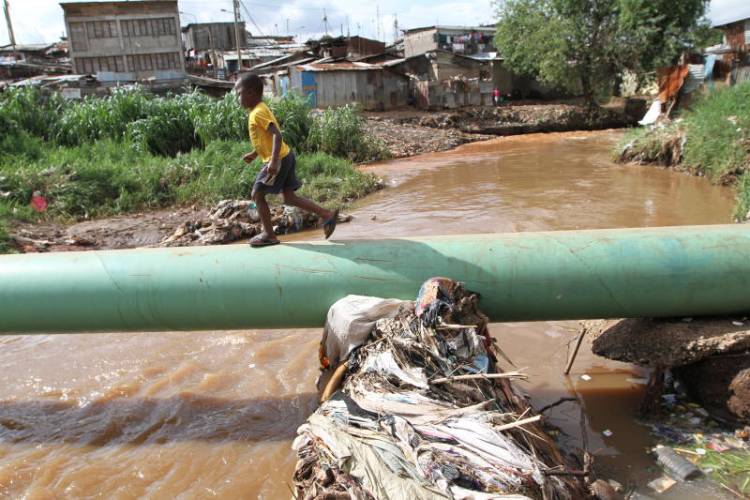Waterway with accumulated waste beside a residential neighbourhood